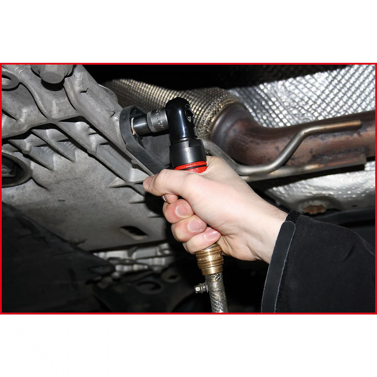 Eine Hand hält einen Druckluftschrauber und schraubt an einem Fahrzeugteil. Der Schrauber hat eine rote Umrandung.